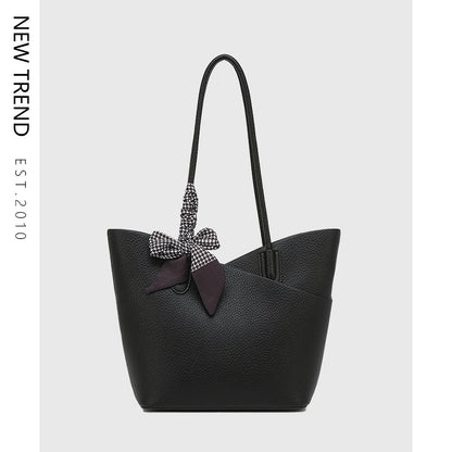Black handbag with a decorative bow on a light gray background