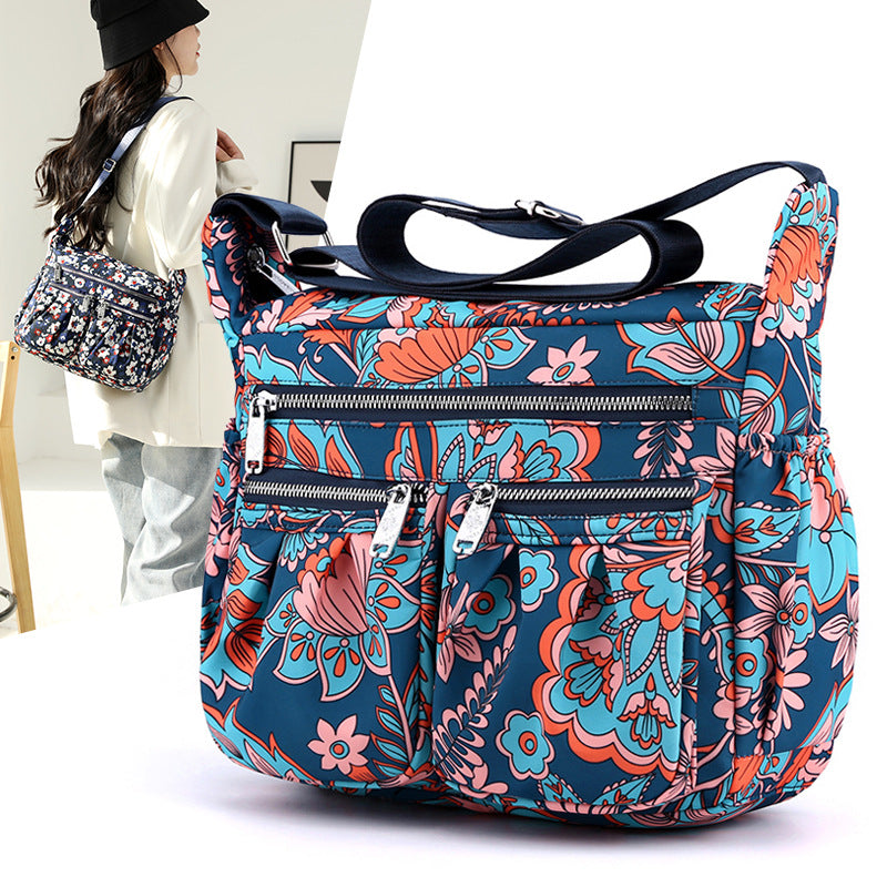 Large-capacity crossbody bag in blue floral print with multiple zip pockets and strap.