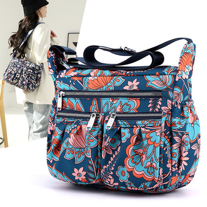 Large-capacity crossbody bag in blue floral print with multiple zip pockets and strap.