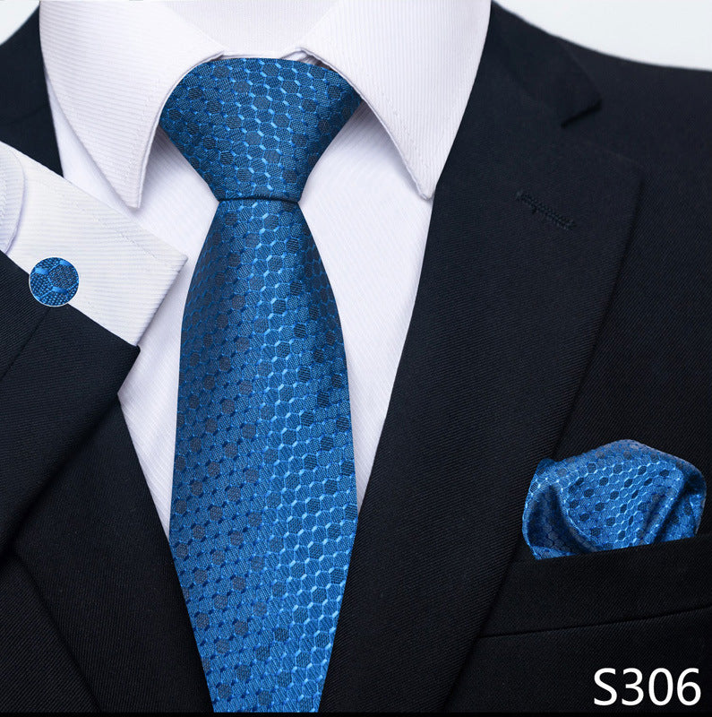 Blue patterned tie, pocket square, and cufflink set on a black suit with white shirt.
