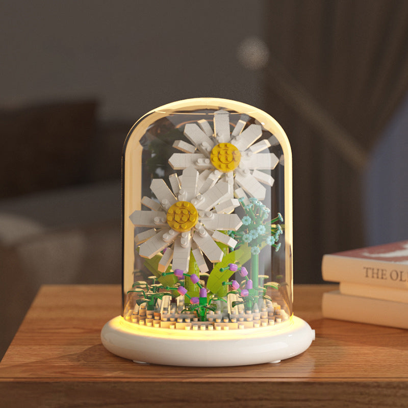 Decorative lamp with flowers inside a glass dome on a wooden surface.
