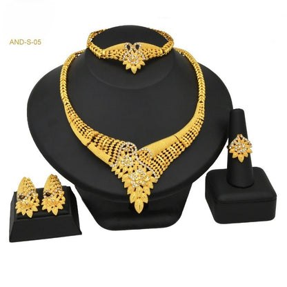 Gold jewelry set including necklace, earrings, and ring on a black stand.