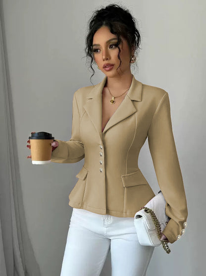 Woman in a beige blazer holding a coffee cup and a white handbag against a neutral background
