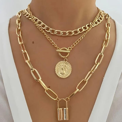 Gold chain necklace with padlock and round pendant on a mannequin