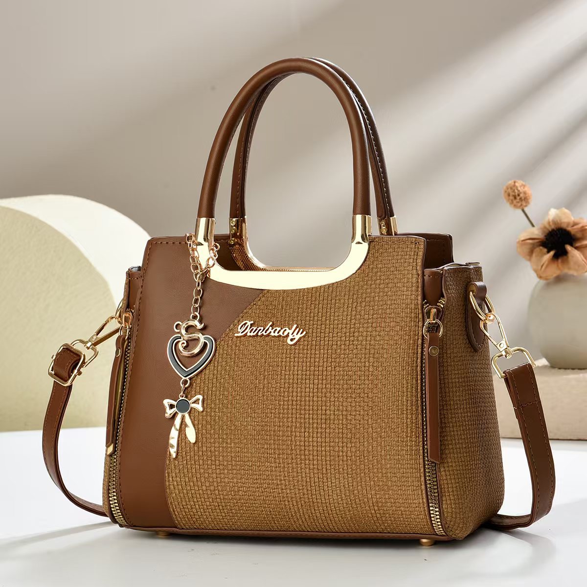 Brown small square crossbody bag with top handles and gold zipper, heart and bow charm