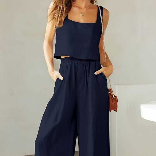 Person wearing a navy blue sleeveless top and wide-leg pants, holding a brown handbag.