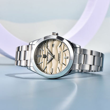 Silver watch with a beige face on a light blue background
