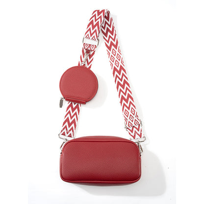 Red handbag with a patterned strap on a white background