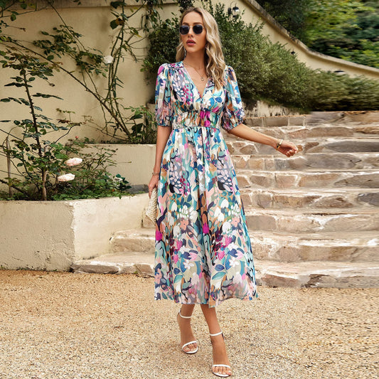 Woman in a floral dress standing on stone steps with greenery in the background