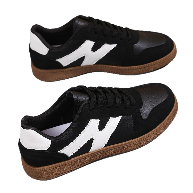 Women's low-top color-block sneakers, black with white side panels and tan gum outsole.