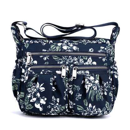 Large-capacity crossbody bag in navy floral print with multiple zip pockets and handles.