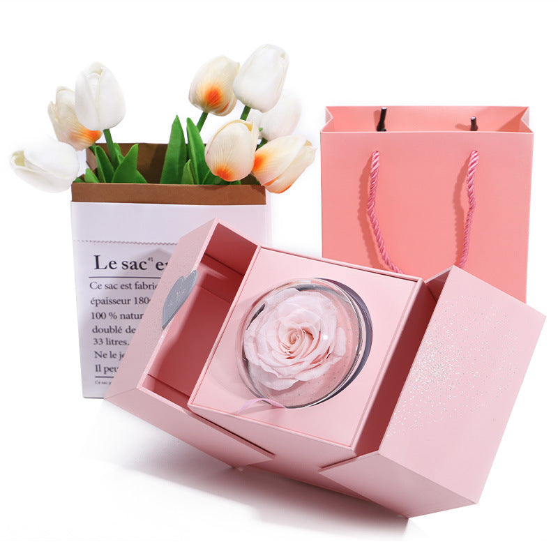 Pink gift box with a preserved rose, white tulips in the background