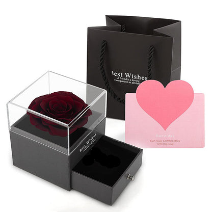 Black gift box with a red rose, black card, and pink heart-shaped card on a white background