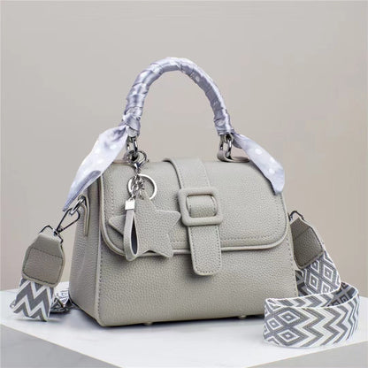 Gray handbag with a decorative strap on a light gray background