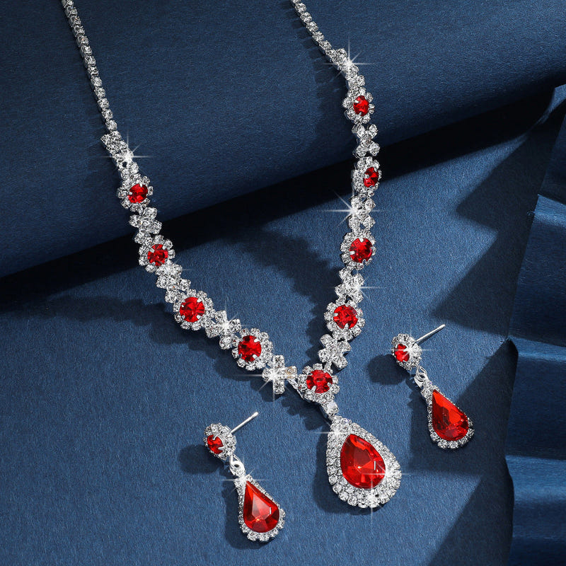 Silver bridal jewelry set with red crystal drop necklace, matching earrings, and bracelet