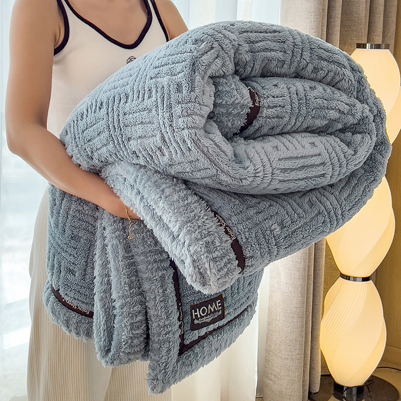 Person holding a textured gray blanket with 'HOME' label in a bright room.