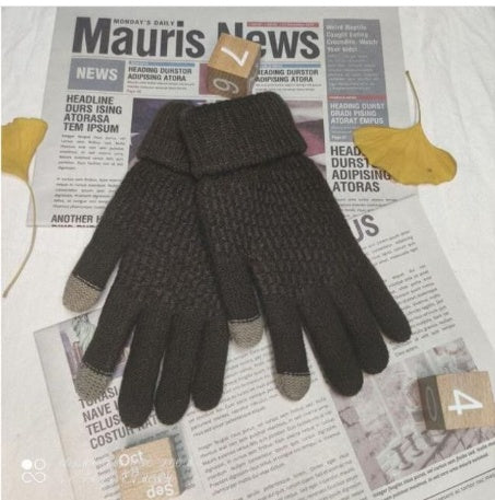 Pair of dark gloves with touchscreen tips on a newspaper background