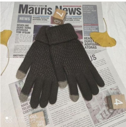 Pair of dark gloves with touchscreen tips on a newspaper background