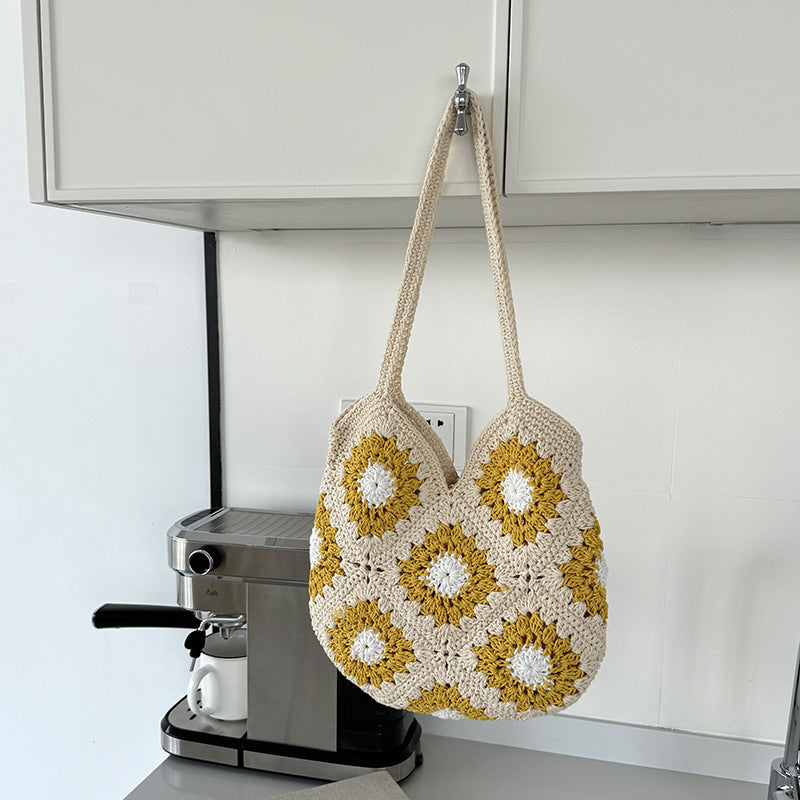 Crocheted bag with floral pattern hanging on a kitchen cabinet.
