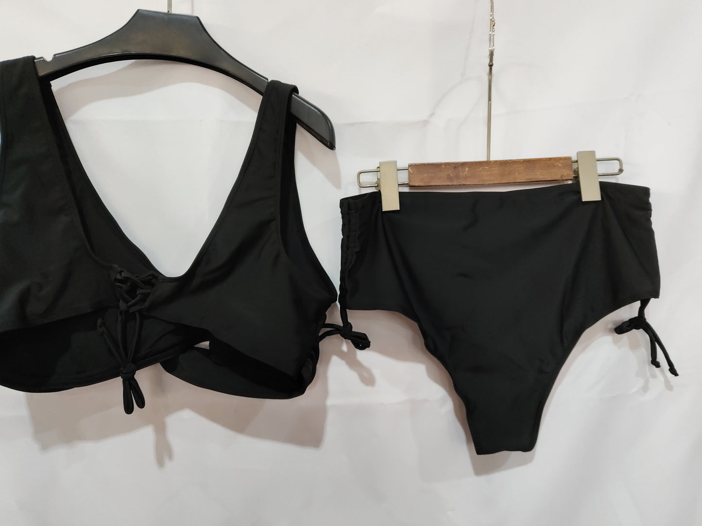 Black bikini set on hangers against a white background