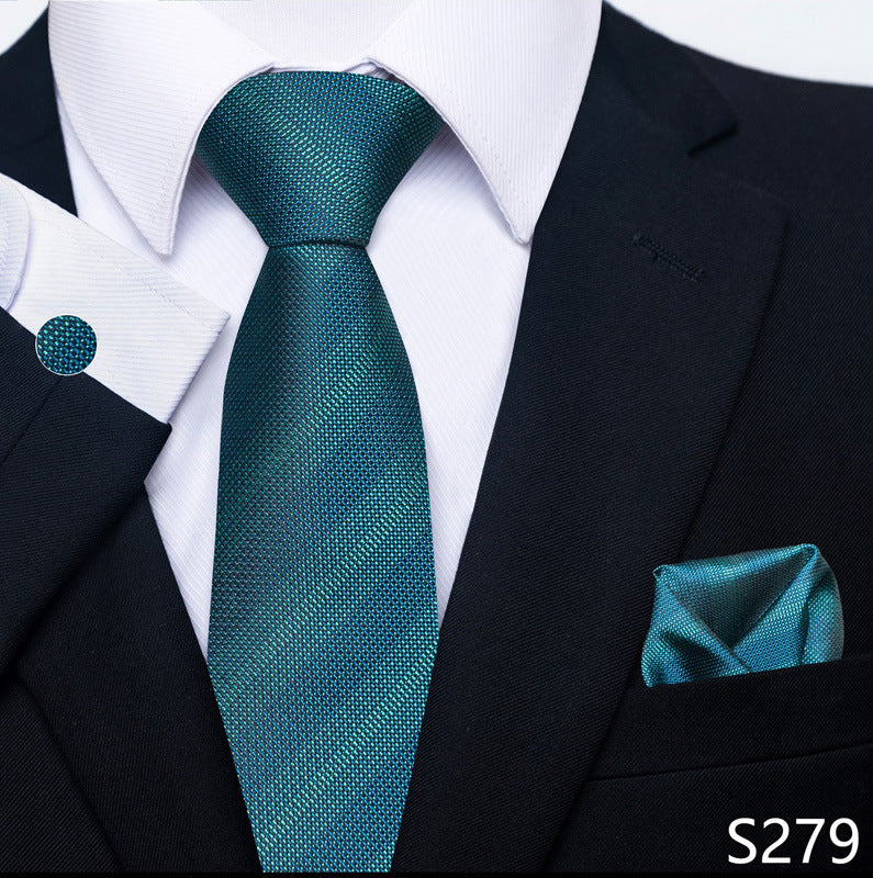 Teal tie, pocket square, and cufflink set on a black suit with white shirt.