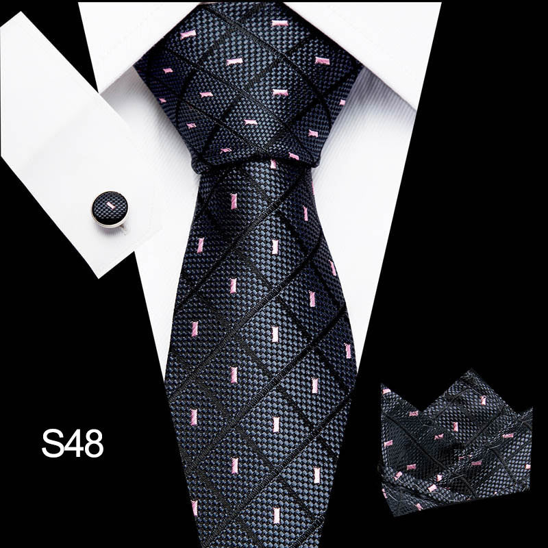 Black patterned tie with matching cufflinks and pocket square on a white background