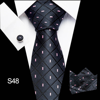 Black patterned tie with matching cufflinks and pocket square on a white background