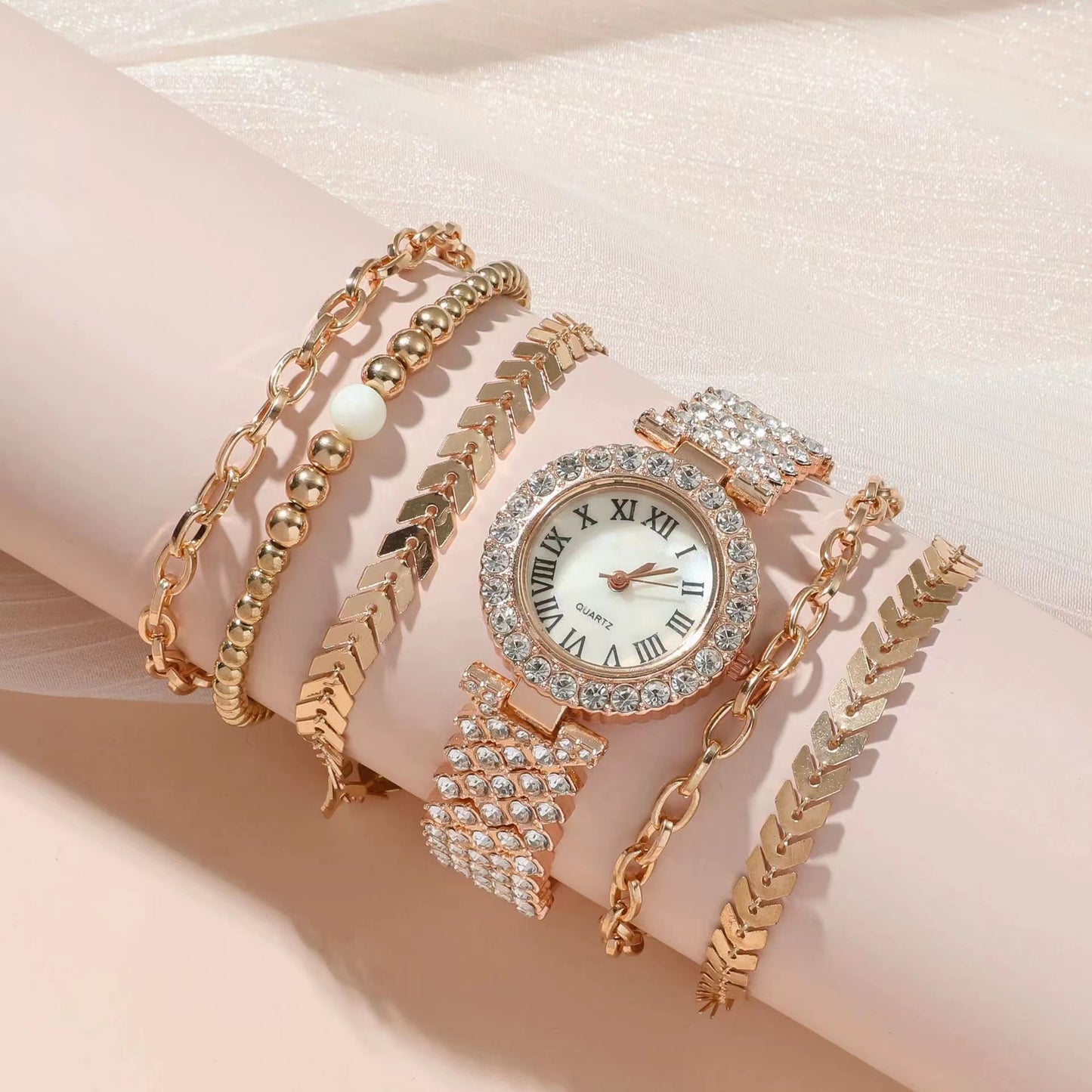 Rose gold watch and bracelet set on a soft pink background