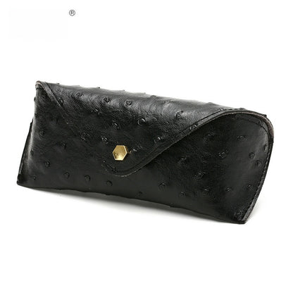 Black ostrich-patterned clutch bag with a gold hexagonal clasp on a white background