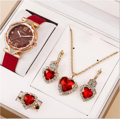 Jewelry set with heart-shaped red gemstones including a watch, necklace, and earrings on a white background.