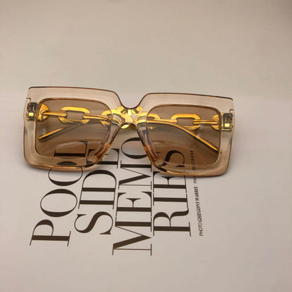 Square tan sunglasses with gold chain detail and amber-tinted lenses