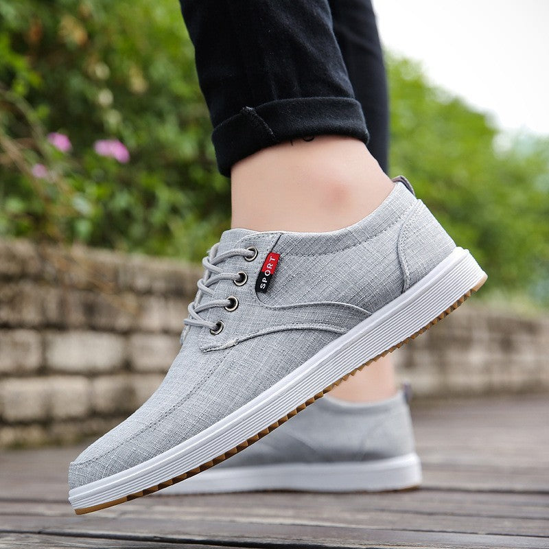 Gray casual shoes with a brand logo worn outdoors on a wooden surface.