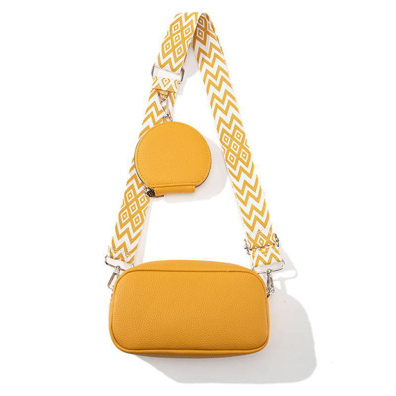 Yellow handbag with a patterned strap on a white background
