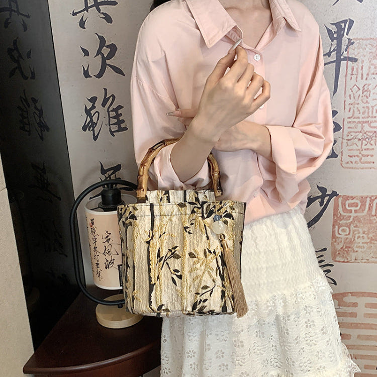 Beige woven handbag with bamboo handles and gold-tone patterned fabric