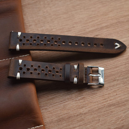 Brown perforated leather watch strap with metal buckle and hole rows, angled view