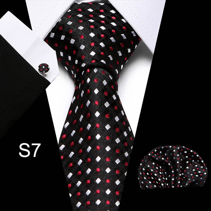 Black tie with red and white pattern, cufflink, and pocket square on a white background