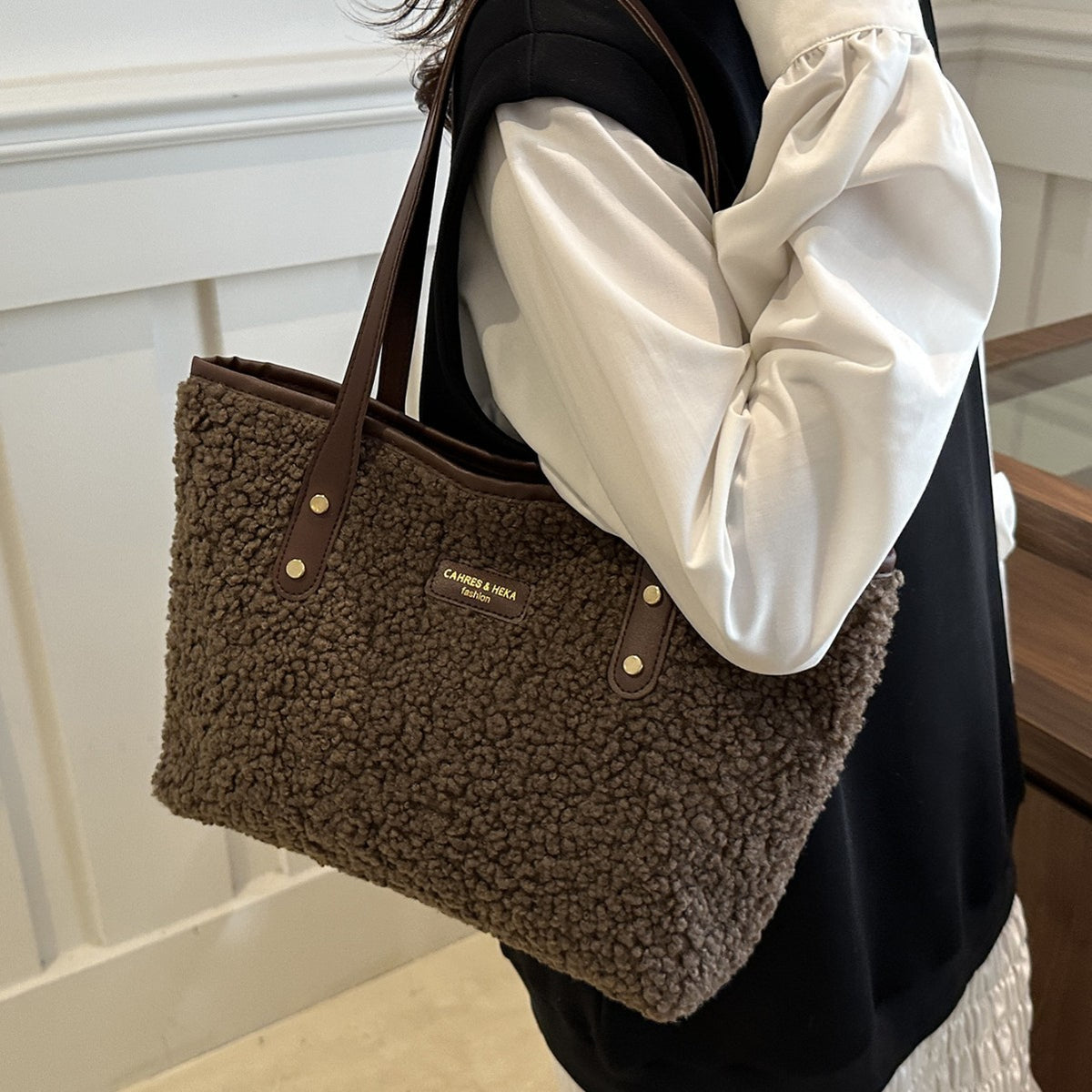 Brown furry tote shoulder bag with dual handles, gold button accents, and front patch