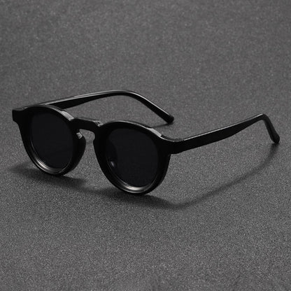 Black round sunglasses on a gray textured background