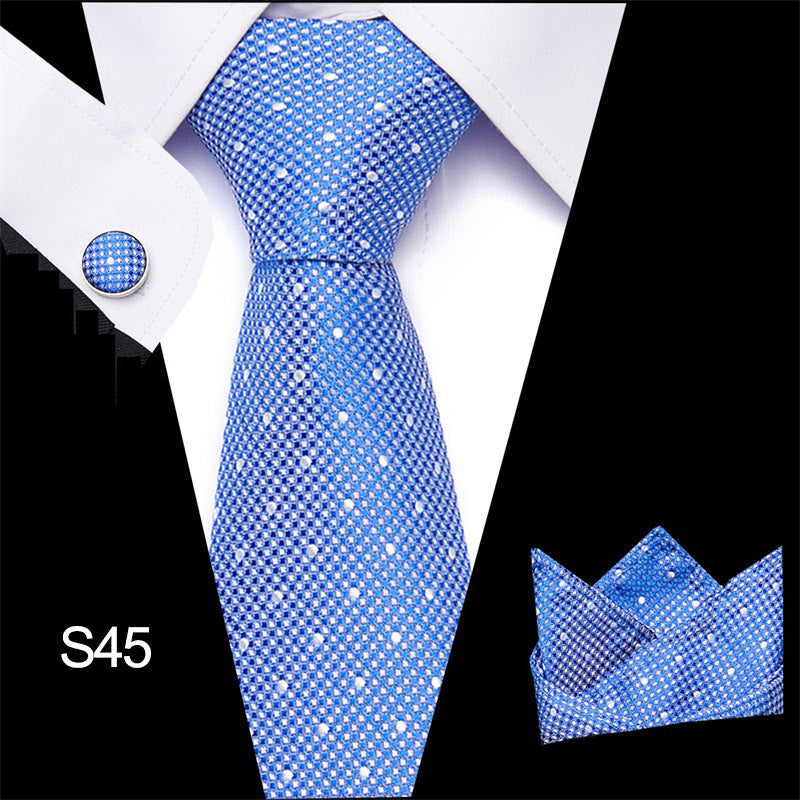 Blue patterned tie set with matching cufflinks and pocket square on a white shirt.