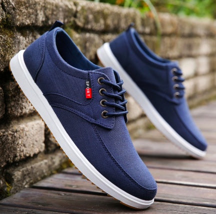 Pair of navy blue sneakers with white soles on a wooden surface.