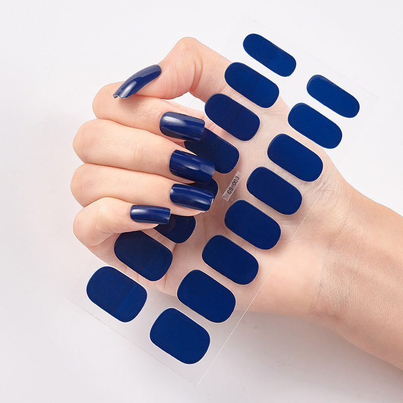 Hand with blue nail polish holding a clear nail wrap sheet.