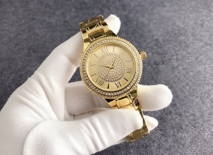 Gold-tone round bracelet watch with ornate bezel, Roman numeral dial, and slim link band