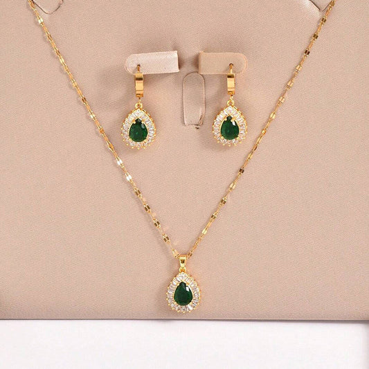 Gold necklace and earrings with green gemstones on a beige background