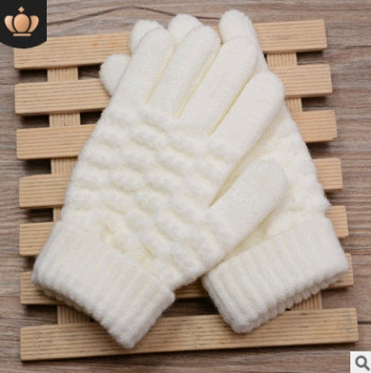 Pair of white knitted gloves on a wooden surface