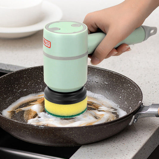 Electric cleaning brush with green handle and yellow sponge head, used on a nonstick pan