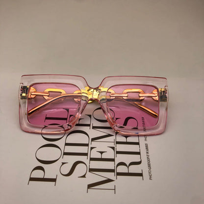 Square pink sunglasses with gold chain detail and pink-tinted lenses