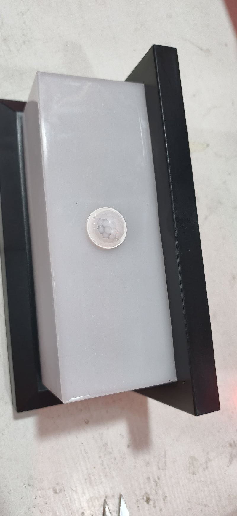 Black outdoor wall lamp with frosted cover and round motion sensor lens