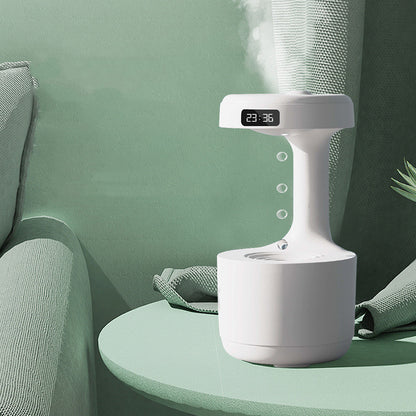 White humidifier with digital display on a green table against a green wall.