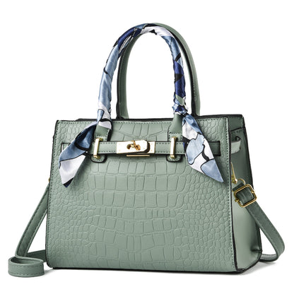 Green handbag with a decorative scarf on a white background