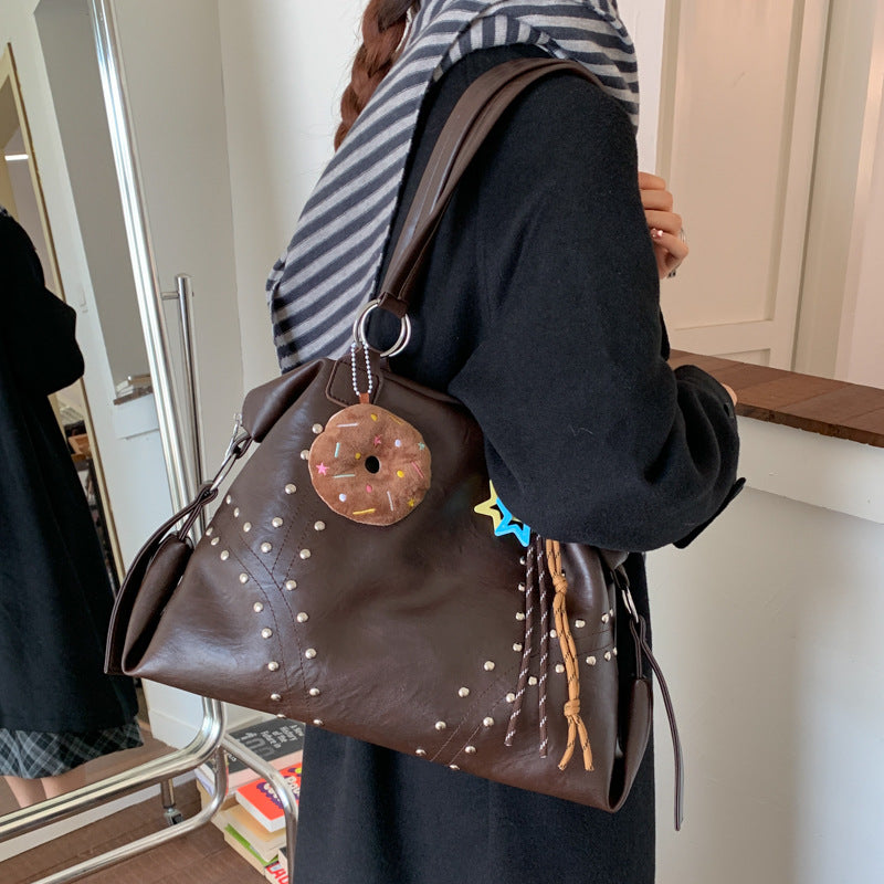 Person holding a brown polka dot handbag with decorative elements indoors.